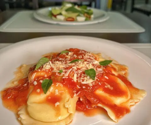 Ravioli ao molho de tomate com queijo ralado e manjericão