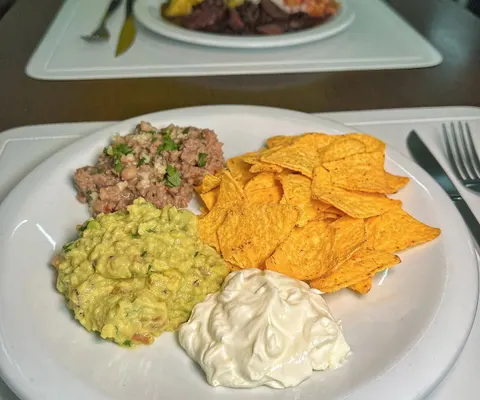 Prato mexicano com carne, guacamole, nachos e creme